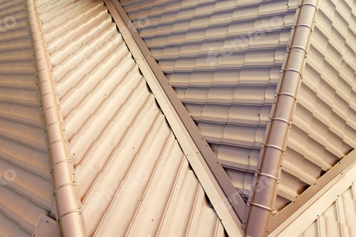 Preview: Detail of a house roof surface covered with brown metal tile sheets.