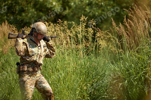 Preview: Portrait of fit military female holding weapon rifle in hands in river, posing alone. Confident