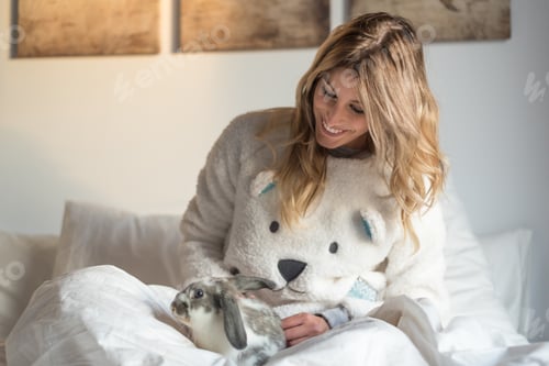 Preview: young beautiful happy blonde women on bed with the bunny