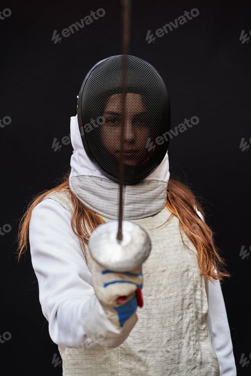 Preview: Portrait of woman dressed in fencing costume on black background.