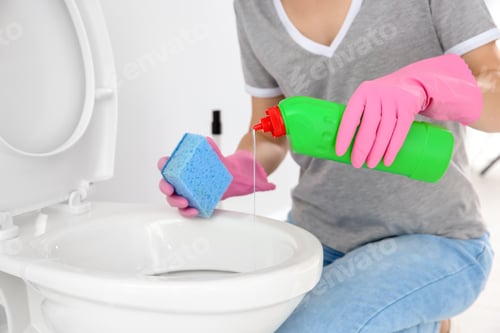 Preview: Woman cleaning toilet bowl in bathroom