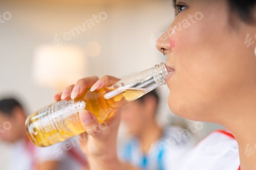 Preview: Woman drinking beer and watching a soccer game