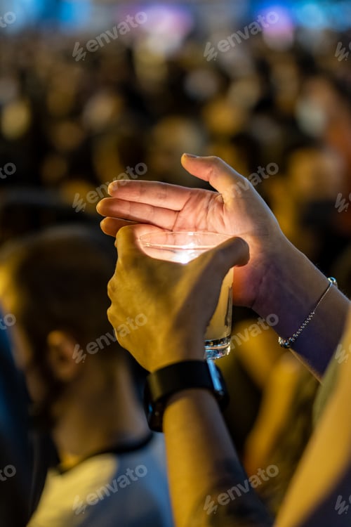 Preview: A hand holding a lighted candle at a demonstration of protesting people