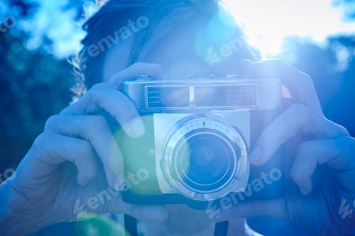 Preview: Woman taking pictures with vintage camera. Backlight. Travel background