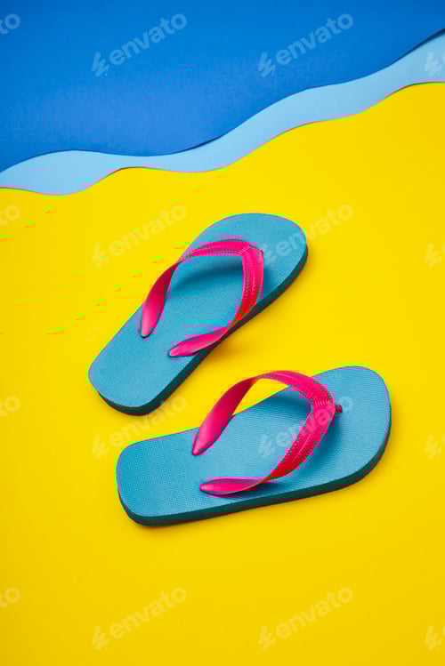 Preview: Pair of colourful flip-flops on sandy beach by sea