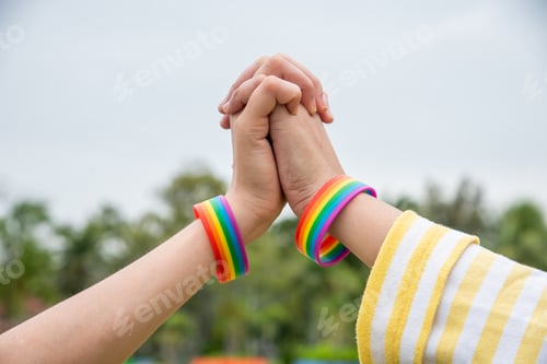 Preview: Two hands holding together wear wrisband Rainbow colored represents the fight, solidarity.nth