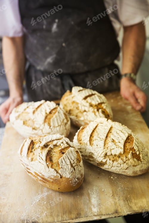 Preview: Baker holding tray with freshly baked loaves of bread