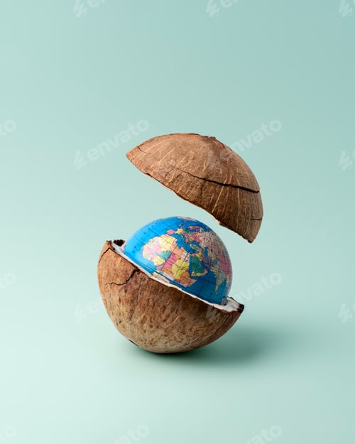 Preview: Coconut shell split open revealing tiny globe inside on mint background in minimal studio setup.