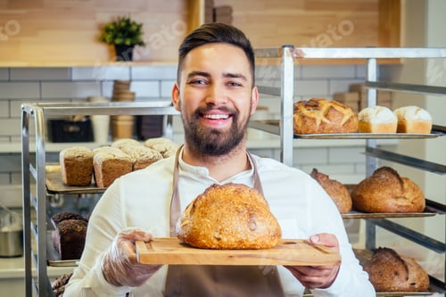 Preview: Handsome baker in uniform at the manufacturing small business owner concept