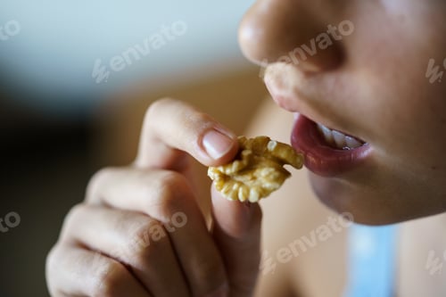Preview: Crop anonymous teenage girl eating healthy walnut kernel
