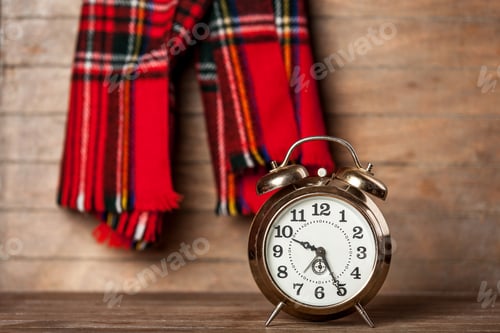 Preview: Retro alarm clock and scarf on wooden table.