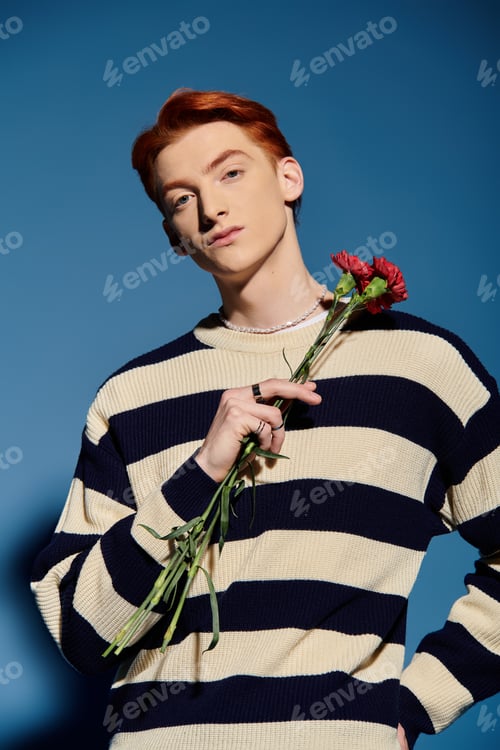 Preview: Emotional young man with red flowers against a vibrant blue backdrop expressing deep feelings