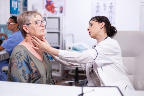 Preview: Young medic palpating neck of senior woman