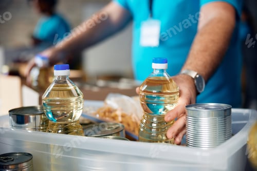 Preview: Close up of volunteer packing food into boxes at donation center.