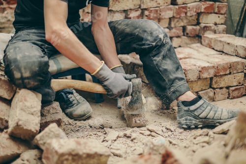 Preview: A young man cleans bricks with an axe.