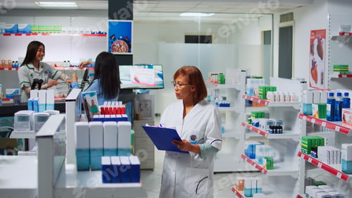Preview: Asian pharmacist working on pills inventory with papers