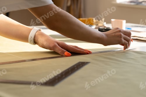 Preview: Creating trendy clothes: closeup of female designer work on draft, fabric on sewing table in studio