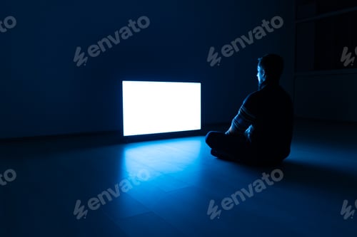 Preview: The man sitting on the floor in front of the television in the dark room