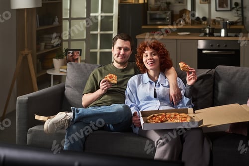 Preview: Young Man and Young Woman Eating Pizza on Sofa Smiling