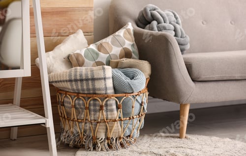 Preview: Basket with blankets and pillows near sofa indoors