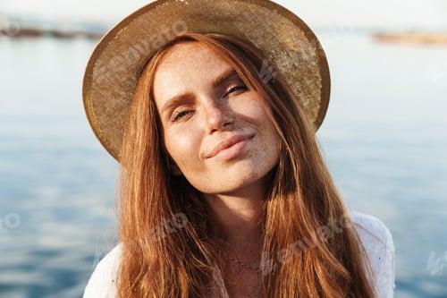 Preview: Image of joyful ginger woman smiling and looking at camera