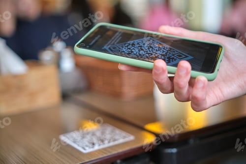 Preview: Closeup of guest hand ordering meal in restaurant while scanning qr code with mobile