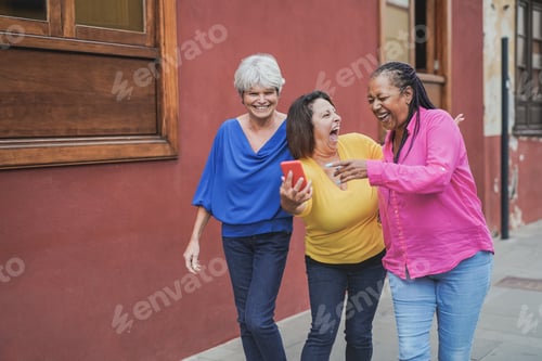 Preview: Multiracial senior women having fun in the city while using mobile phone
