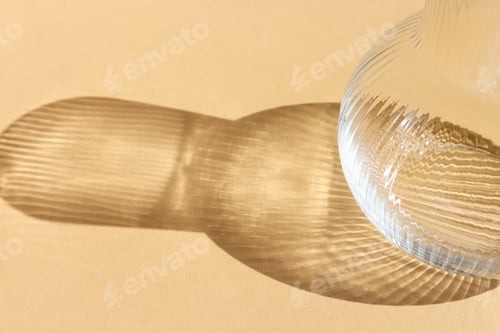 Preview: Abstract background with a shadow from a glass vase on a beige wall.