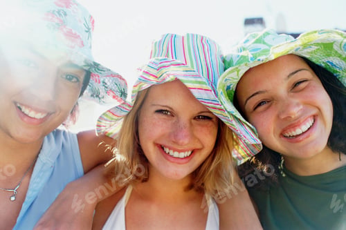 Preview: Three young girls in a row wearing sunhats looking at the camera and smiling.