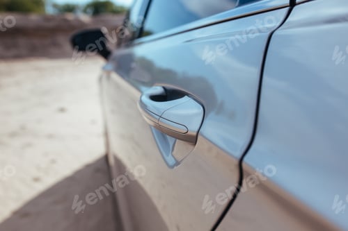 Preview: door handle of a gray passenger car standing on the sand