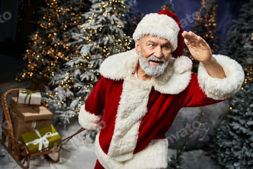 Preview: Santa Claus joyfully waves in a snowy wonderland filled with festive decorations and gifts