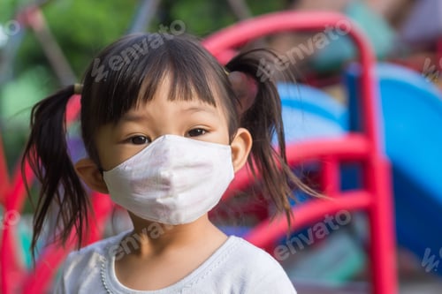 Preview: Asian child girl wearing fabric face mask. She play the ball toy at the green park playground