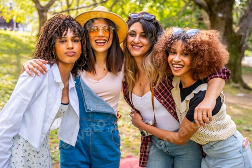 Preview: Four young women embracing in a park, celebrating friendship