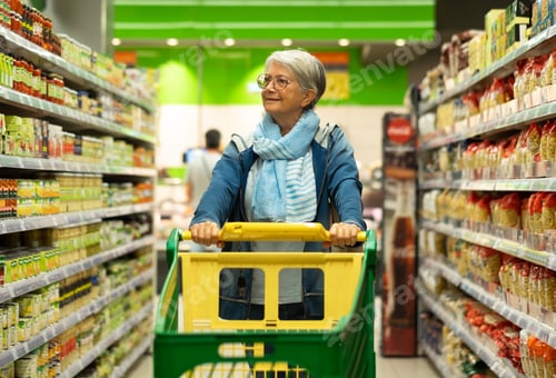 Preview: Retired senior woman pushing shopping trolley in supermarket shopping for groceries