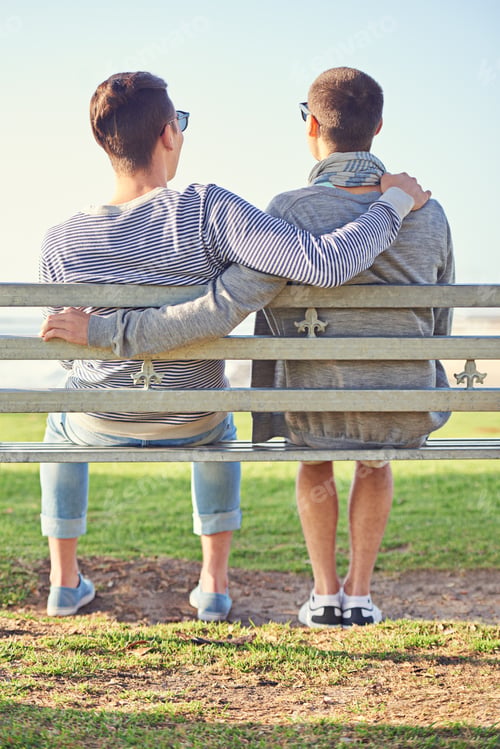 Preview: Rearview shot of a young gay couple sitting together on a park bench
