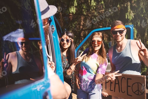 Preview: Young boho hitchhikers with peace sign by recreational van