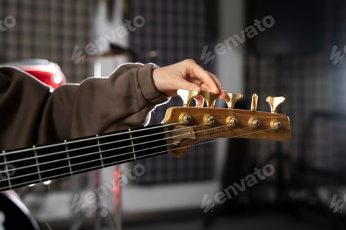 Preview: a Musician Fine-Tuning Acoustic Guitar Strings in a Dimly Lit Room of music studio