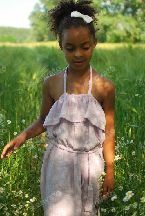Preview: Girl of mixed race walking in a summer barley field wearing a summer dress - daisy sunset