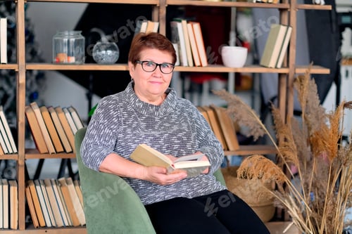 Preview: Beautiful old woman in casual clothes reading on couch at home. look at camera smiling.