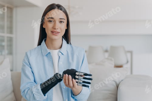 Preview: Happy disabled young woman is assembling bionic limb prosthesis. Attractive girl has cyber hand.