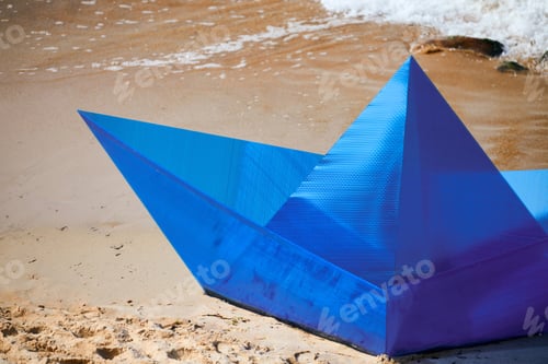 Preview: Origami blue paper boat on sandy beach for concept design, beautiful blue paper ship, close up