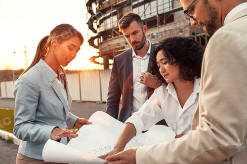 Preview: Business people discussing a blueprint in front of the construction site.