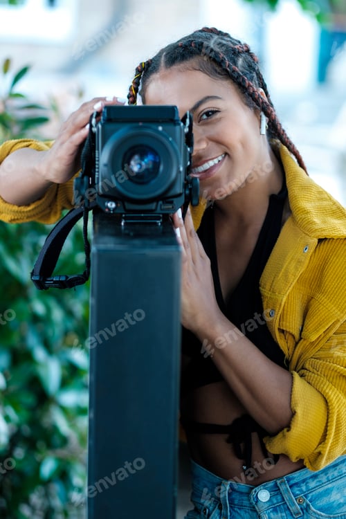 Preview: Young woman using a big analog camera.