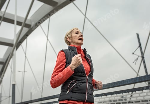 Preview: Active senior woman running through the city during the day.
