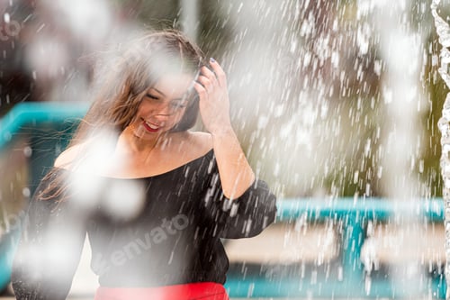 Preview: Joyful Woman Playing in Splashing Water at Outdoor Park in Bright Sunshine