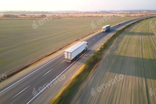 Preview: Aerial view of cargo trucks driving on highway hauling goods.