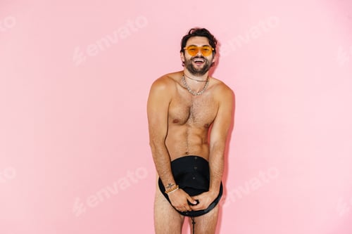 Preview: Young naked man in sunglasses laughing while covering hat
