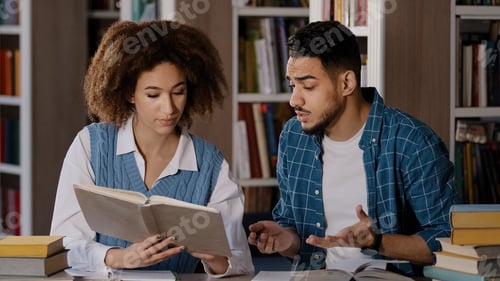 Preview: Students studying in library doing homework preparing for exam young girl reads textbook searches