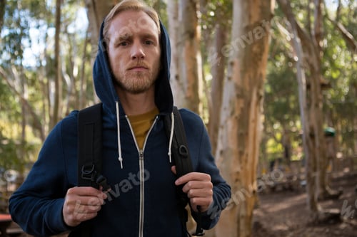 Preview: Young hiker man with backpack standing in the forest on a sunny day
