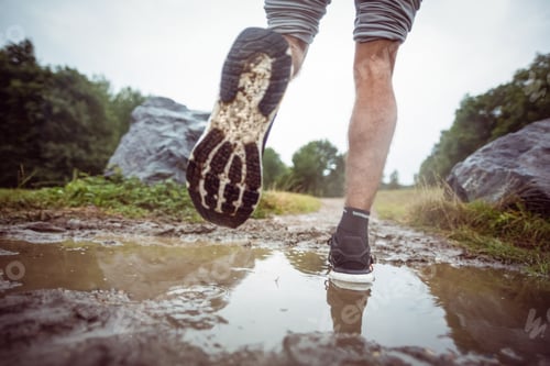 Preview: Man jogging through muddy puddles in the countryside